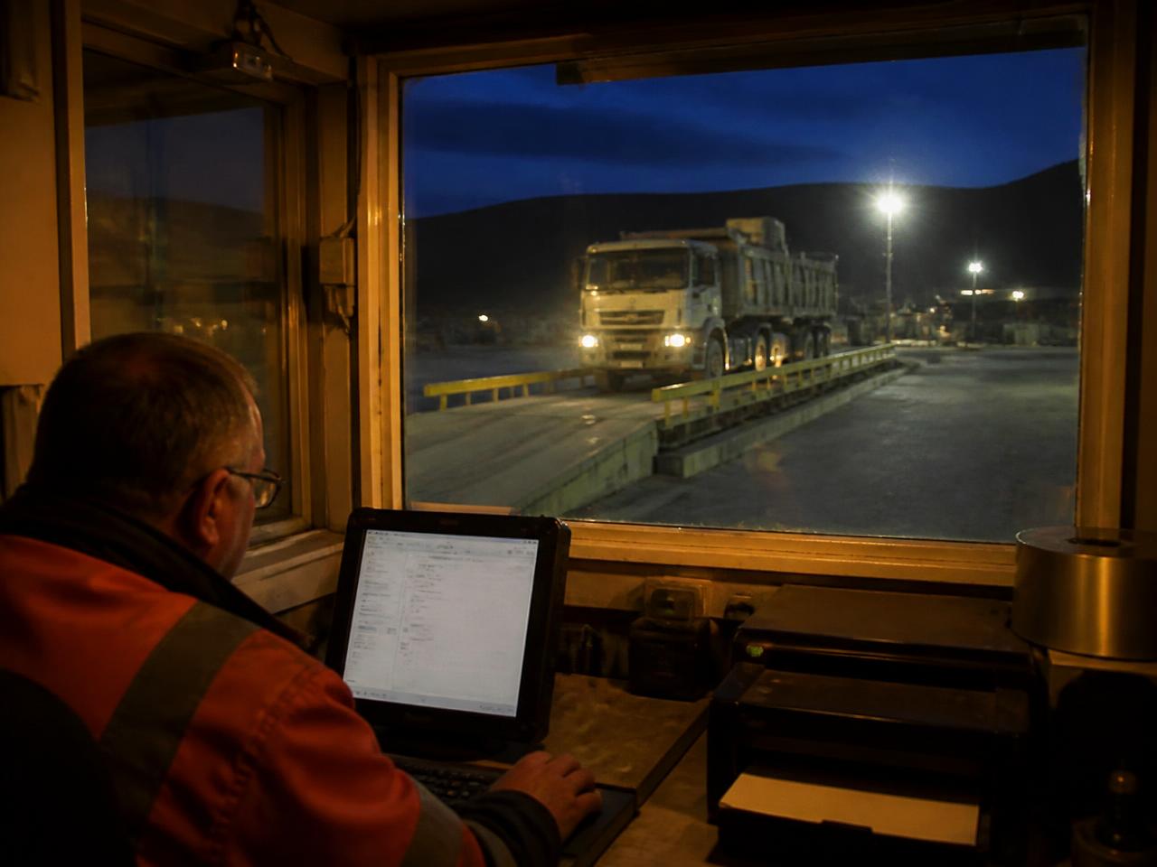 Operator recording a weigh ticket in a quarry scale house at dusk